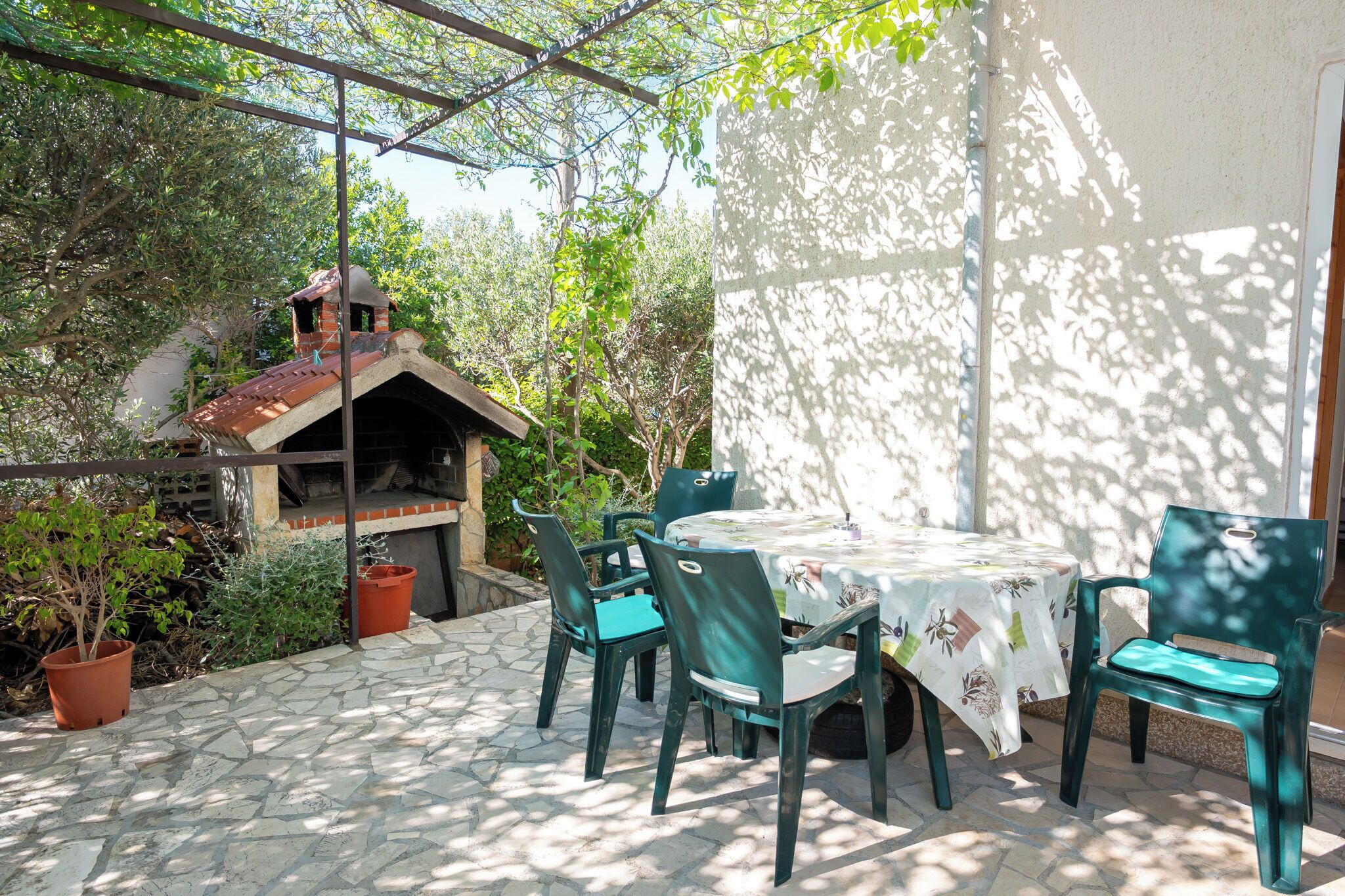 Eine Terrasse mit Tisch, Stühlen, einem Backofen aus Ziegeln und Topfpflanzen.
