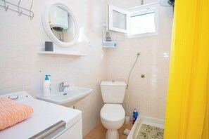 A bathroom with a toilet, sink, mirror, and a window. - Apartments Olive and Sea (Solta)