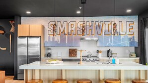 Uma cozinha moderna com uma ilha central, banquetas de bar e um grande mural de paisagem urbana na parede.