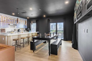 A modern kitchen with a bar area, city views through large windows, and a black and white color scheme. - Neon & Nashville | 8BR, Pool Table, Balconies (Nashville)