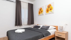 Ein Schlafzimmer mit einem Bett, einem Nachttisch mit Lampe, einem Beistelltisch und zwei an der Wand hängenden Bildern.