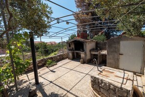 Eine Terrasse mit Grill, Steinmauern und Blick auf die umliegende Landschaft.