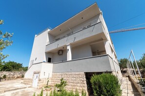 A multi-story building with a balcony, a stone base, and a clear sky. - Apartment Rooftop Valerija (Okrug)