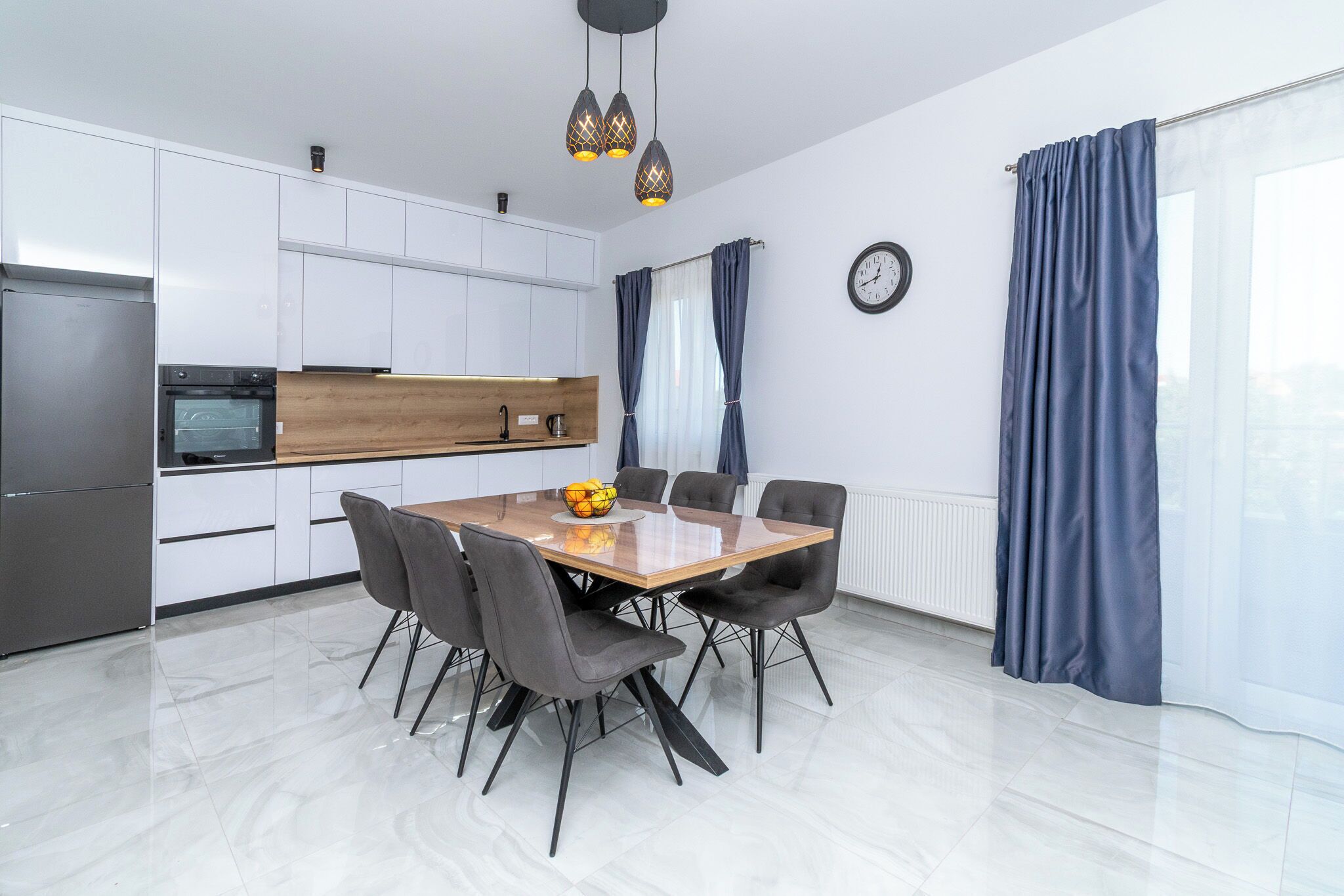 A modern kitchen with white cabinets, a wooden countertop, and a dining table with chairs.