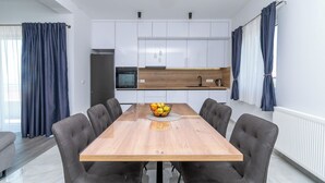 Eine moderne Küche mit weißen Schränken, einem Holztisch und einer Obstschale.