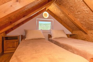 A bedroom with two beds, wooden headboards, a window with a view, and a circular light fixture. - House Romance for two (Lovreć)
