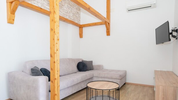 A modern living room with a sectional sofa, a round wooden coffee table, and a TV mounted on the wall. - Apartment Adriatic Panorama (Podstrana)