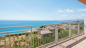 A balcony with a view of the sea and distant buildings. - Apartment Adriatic Panorama (Podstrana)