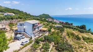 A coastal property with a large white building, a paved driveway, and a view of the sea. - Apartment Adriatic Panorama (Podstrana)