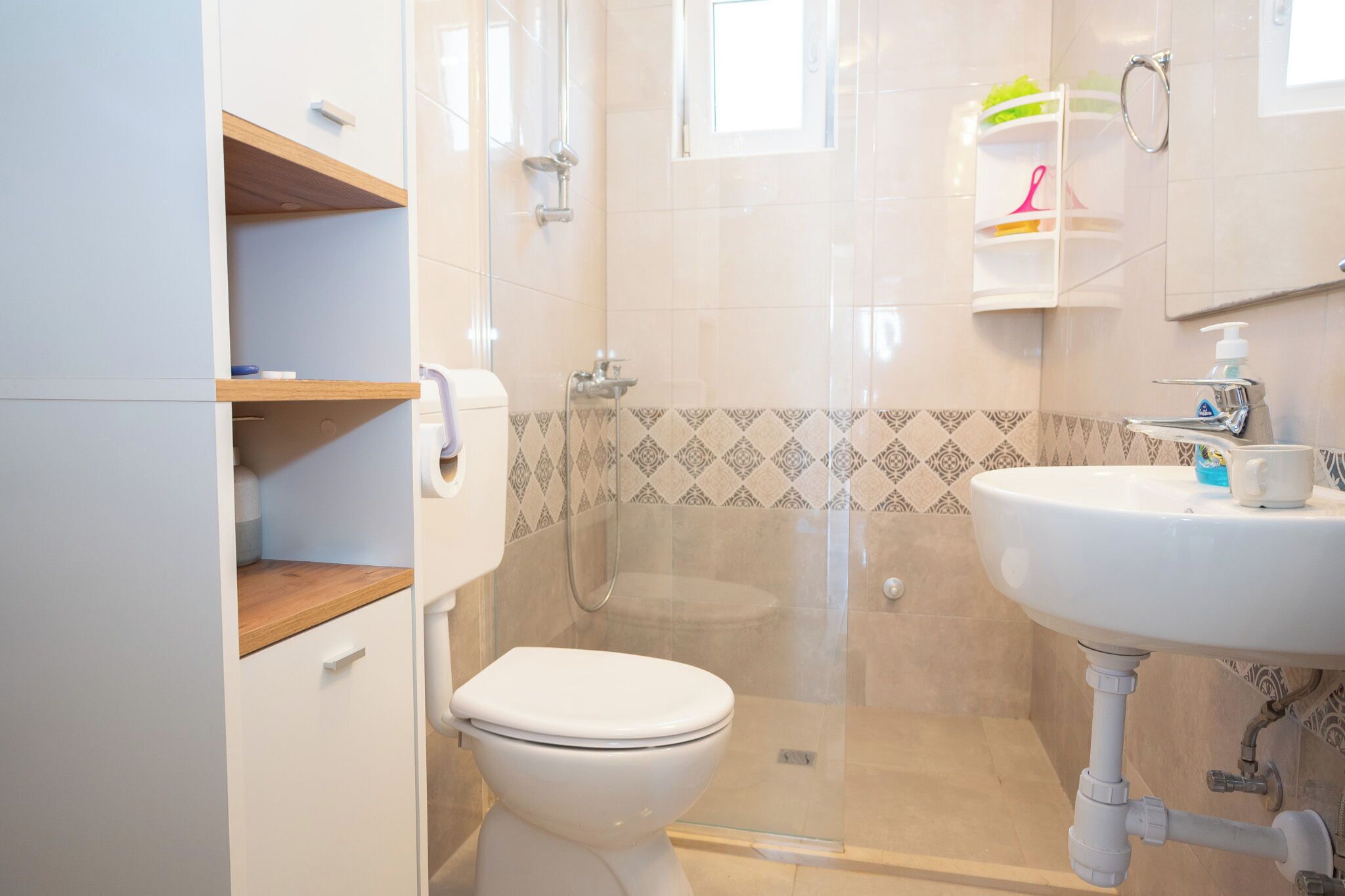 Une salle de bain comprenant des toilettes, un espace douche, un lavabo et un miroir.