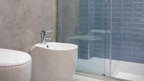 A bathroom with a toilet, a bidet, and a glass-enclosed shower area.