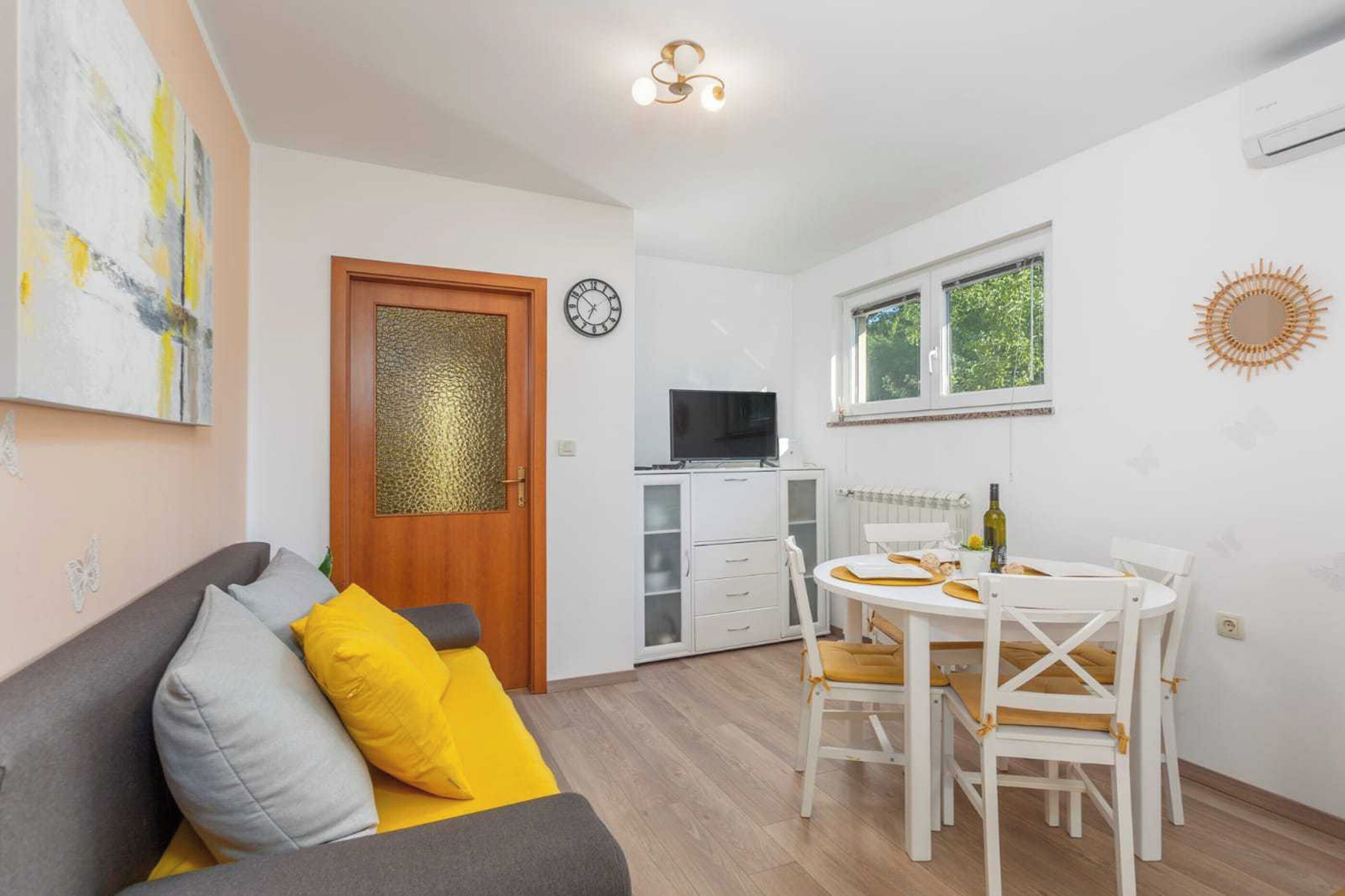 A compact living space with a sofa, a dining table, a TV, and a window.