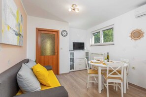 A compact living space with a sofa, a dining table, a TV, and a window. - Apartment Nature (Klana)