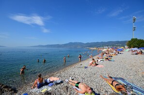 A pebbled beach with people sunbathing and swimming. - Apartment Nature (Klana)