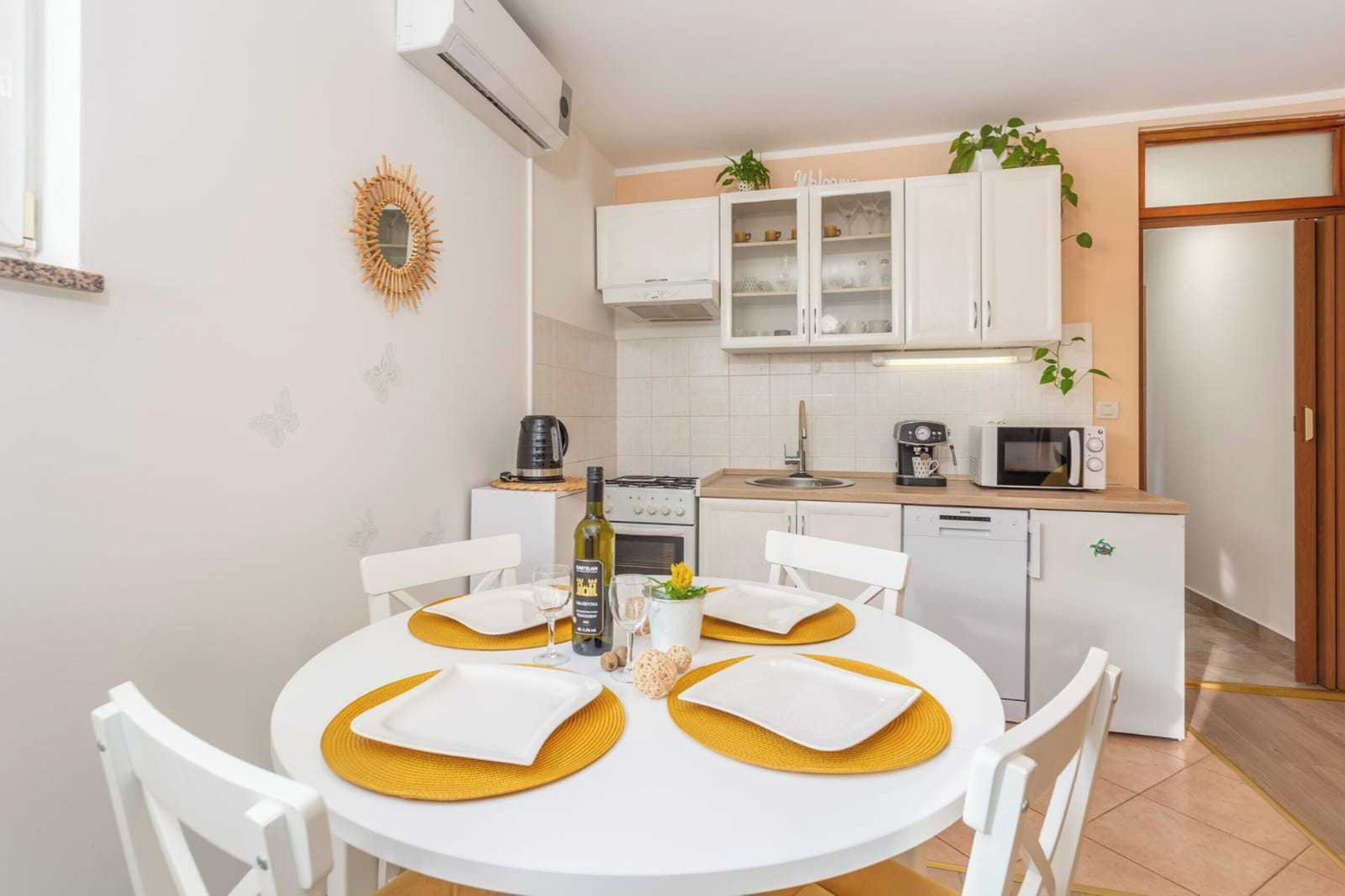 A compact kitchen with white cabinets, a microwave, a coffee maker, and a dishwasher.
