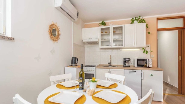 A compact kitchen with white cabinets, a microwave, a coffee maker, and a dishwasher. - Apartment Nature (Klana)