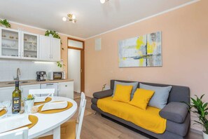 A modern apartment with a dining area, kitchenette, sofa, and abstract art. - Apartment Nature (Klana)
