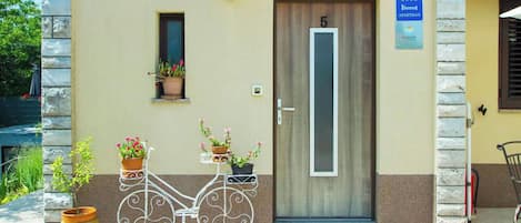 Un immeuble avec une porte portant le numéro « 5 », une enseigne indiquant « APPARTEMENT » et un paillasson.