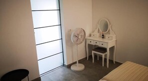 A bedroom with a white vanity, a mirror, a fan, and a bed. - Apartments Zanoff (Umag)