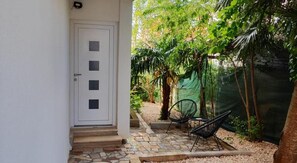 A white door with four panels, a stone-paved entrance, and a small outdoor seating area with chairs. - Apartments Casa Zanoff (Umag)