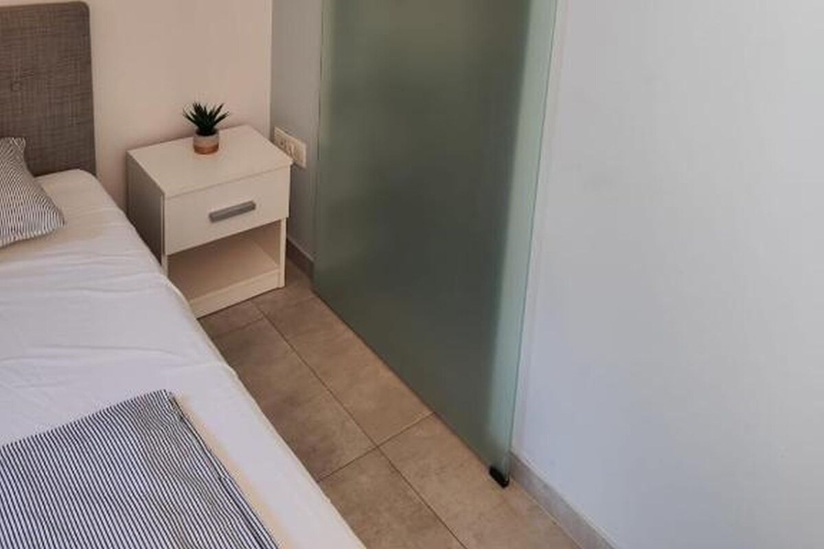 A bedroom with a bed, bedside table, and a sliding door.