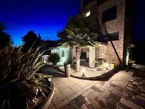 A stone building with a patio area, a palm tree, and a small outdoor seating area. - Apartments Zanoff (Umag)