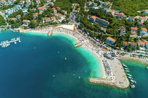Eine Vogelperspektive auf eine Küstenstadt mit Strand, Booten und Wohnhäusern.