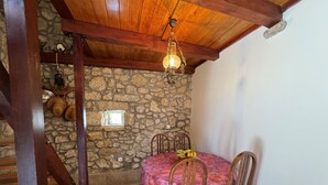 A stone-walled room with a wooden ceiling, a table with a pink tablecloth, and a hanging light fixture. - Apartment Prelec (Crikvenica)