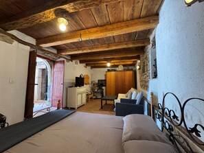 Una habitación rústica con una cama, un sofá, una mesa de comedor y una pared de piedra.
