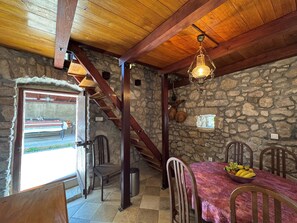 Un comedor rústico con paredes de piedra, vigas de madera y una escalera.