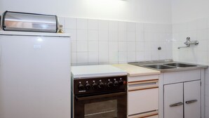 Una cucina con un frigorifero bianco, un fornello, un forno, un lavello e una lampada sopra il bancone.