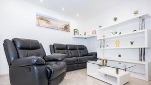 A modern living room with two leather recliners, a glass coffee table, and a white shelving unit with decorative items. - House Danijel (Novi Vinodolski)