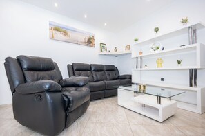 A modern living room with two leather recliners, a glass coffee table, and a white shelving unit with decorative items. - House Danijel (Novi Vinodolski)
