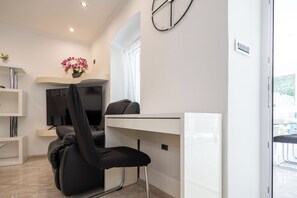 Ein modernes Zimmer mit einem Bett, einem Schreibtisch, einem Stuhl, einem Fernseher und einem Fenster.