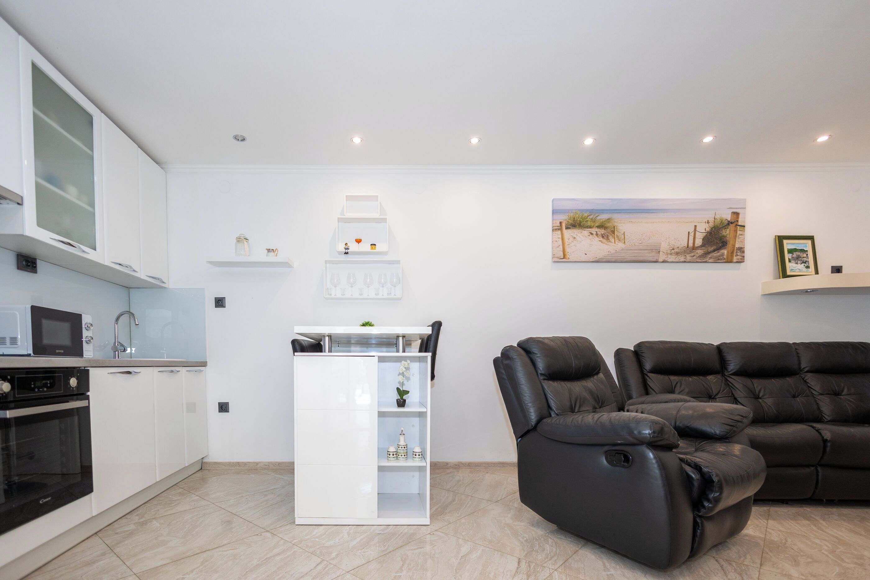 A modern kitchen with white cabinets, a built-in microwave, and a black oven.