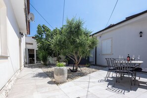 A patio area with a dining table and chairs, a potted plant, and a small tree. - House Danijel (Novi Vinodolski)