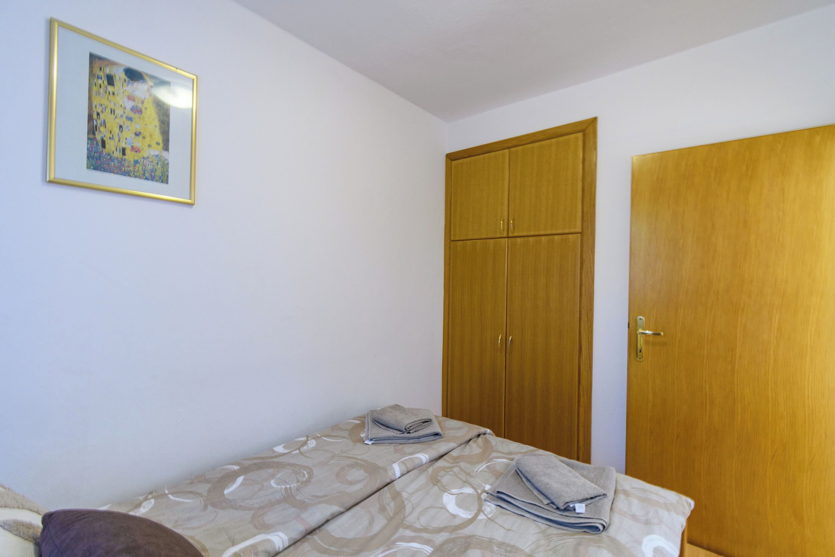 Ein Schlafzimmer mit einem Bett, einem Kleiderschrank und einem gerahmten Bild an der Wand.