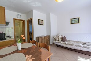 A compact living space with a kitchenette, dining area, and a bed. - Apartments Tomo (Lopar)