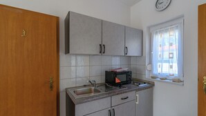 Une cuisine avec des meubles de couleur grise, un four à micro-ondes et un évier.
