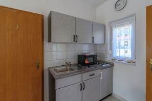 Una cocina con gabinetes grises, un microondas y un fregadero.