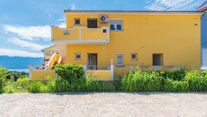 Un edificio amarillo con un balcón, una ventana pequeña y una puerta.