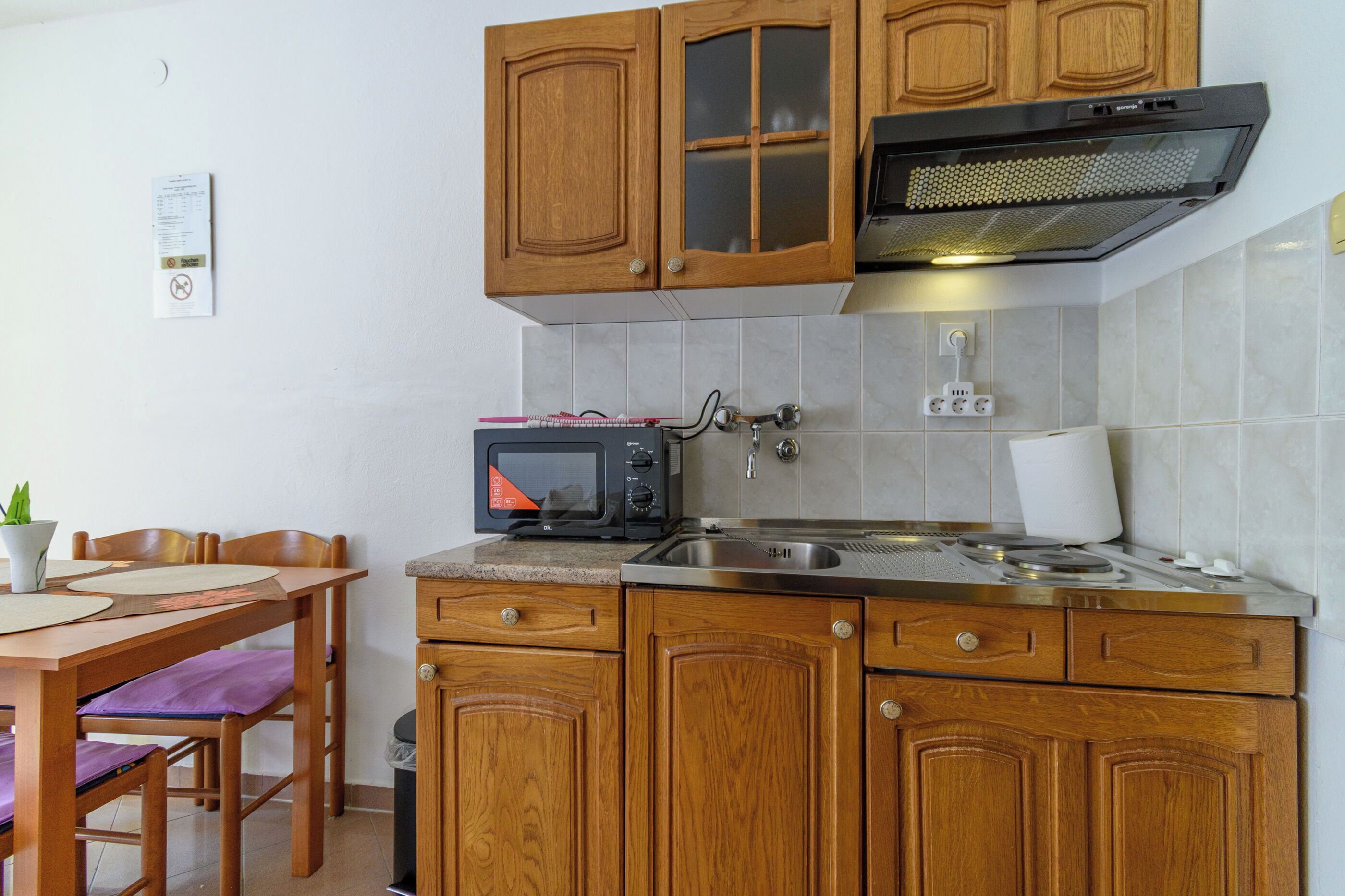 Une cuisine avec des meubles de rangement en bois, un four à micro-ondes, un évier et une cuisinière.