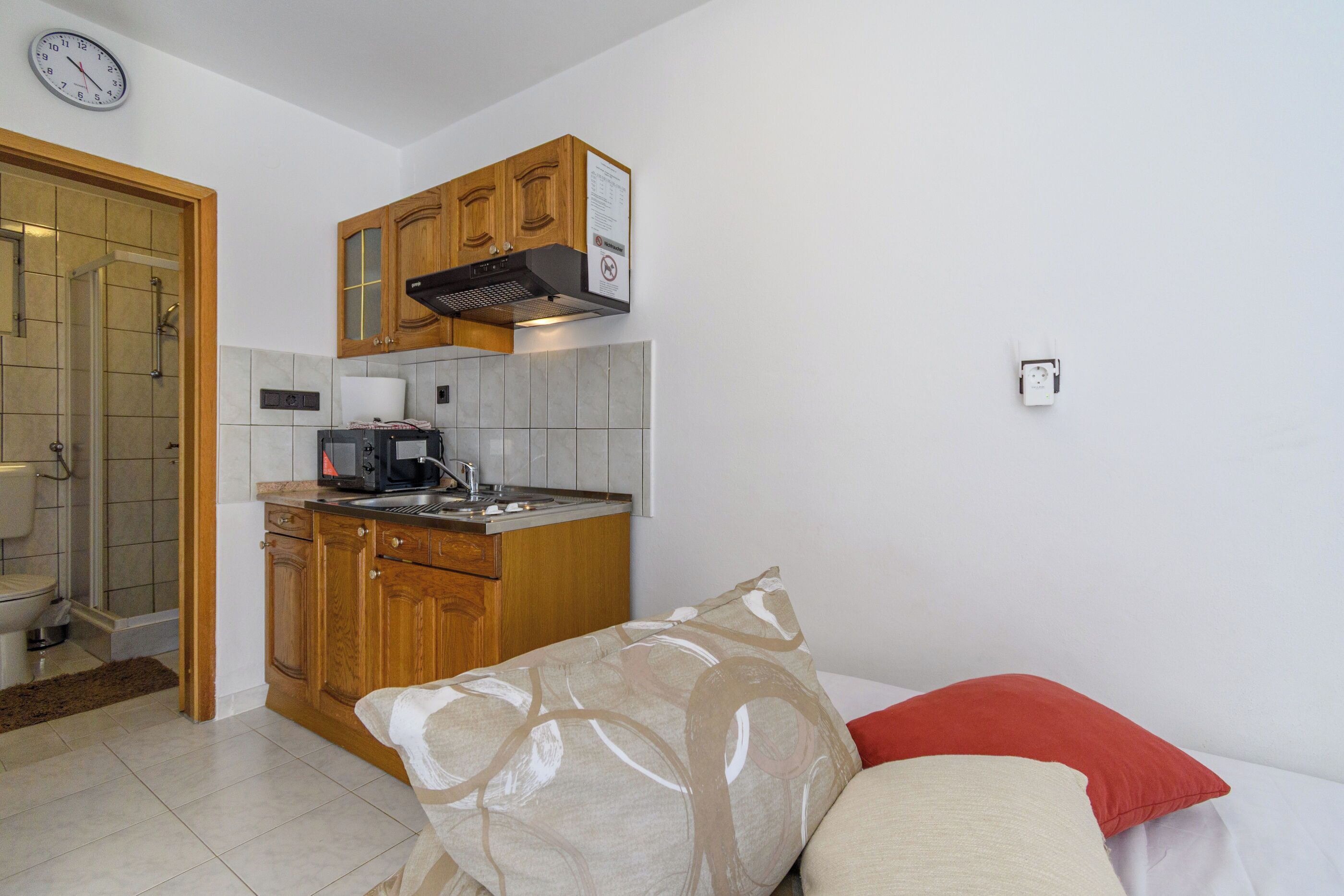 A compact kitchen with wooden cabinets, a microwave, and a built-in oven.