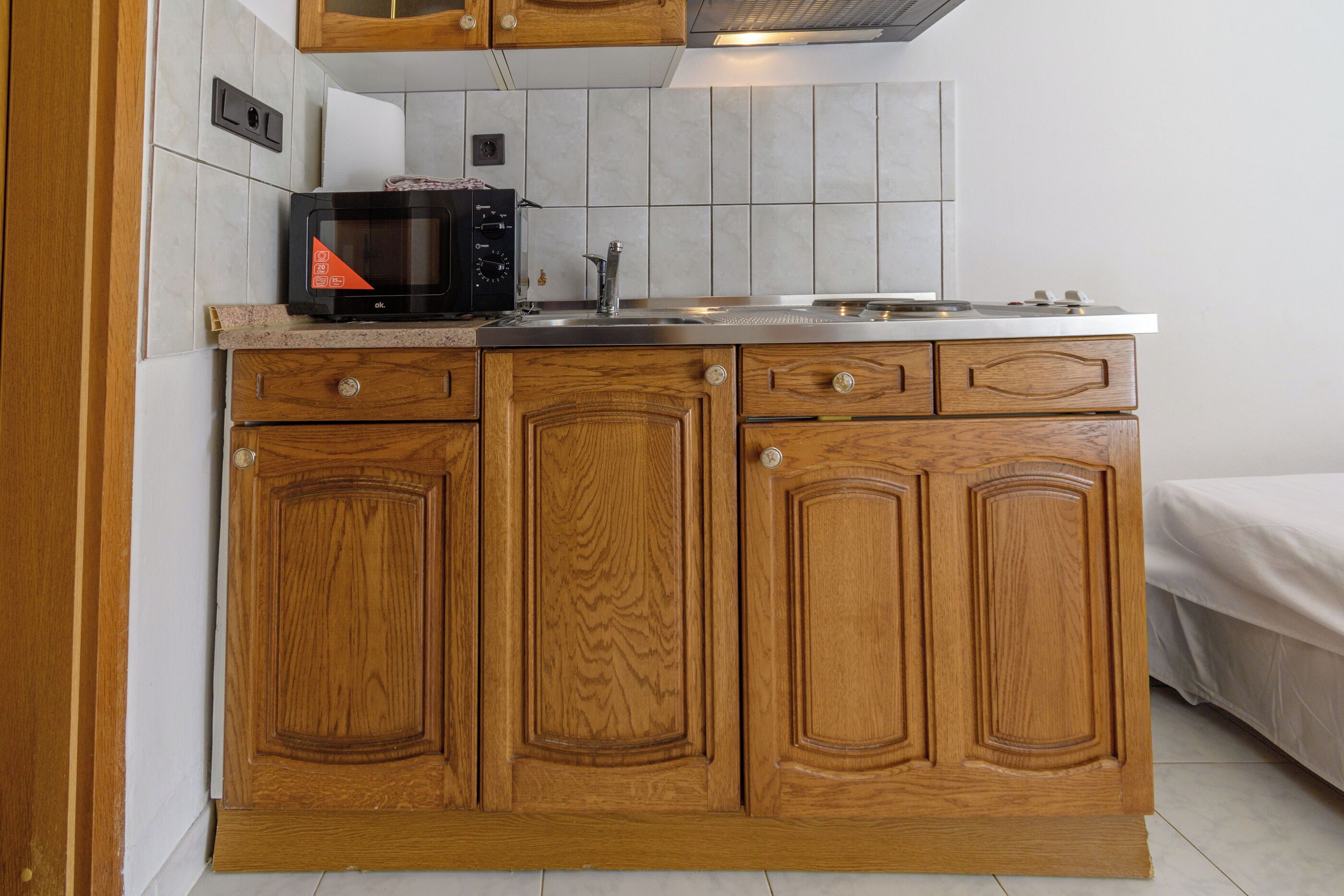 A compact kitchen with wooden cabinets, a microwave, and a sink.
