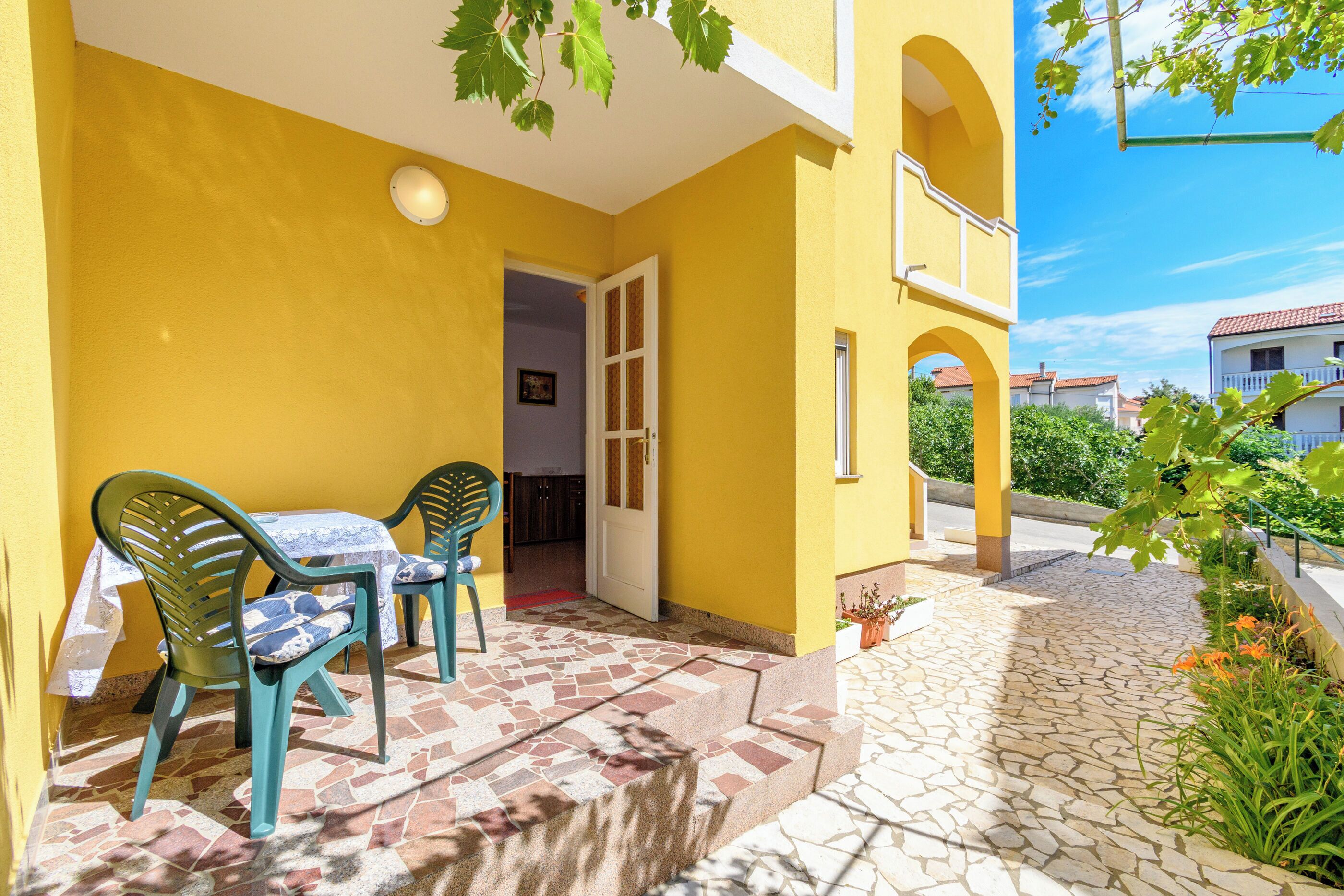 A yellow building with a patio, outdoor seating, and a stone pathway.