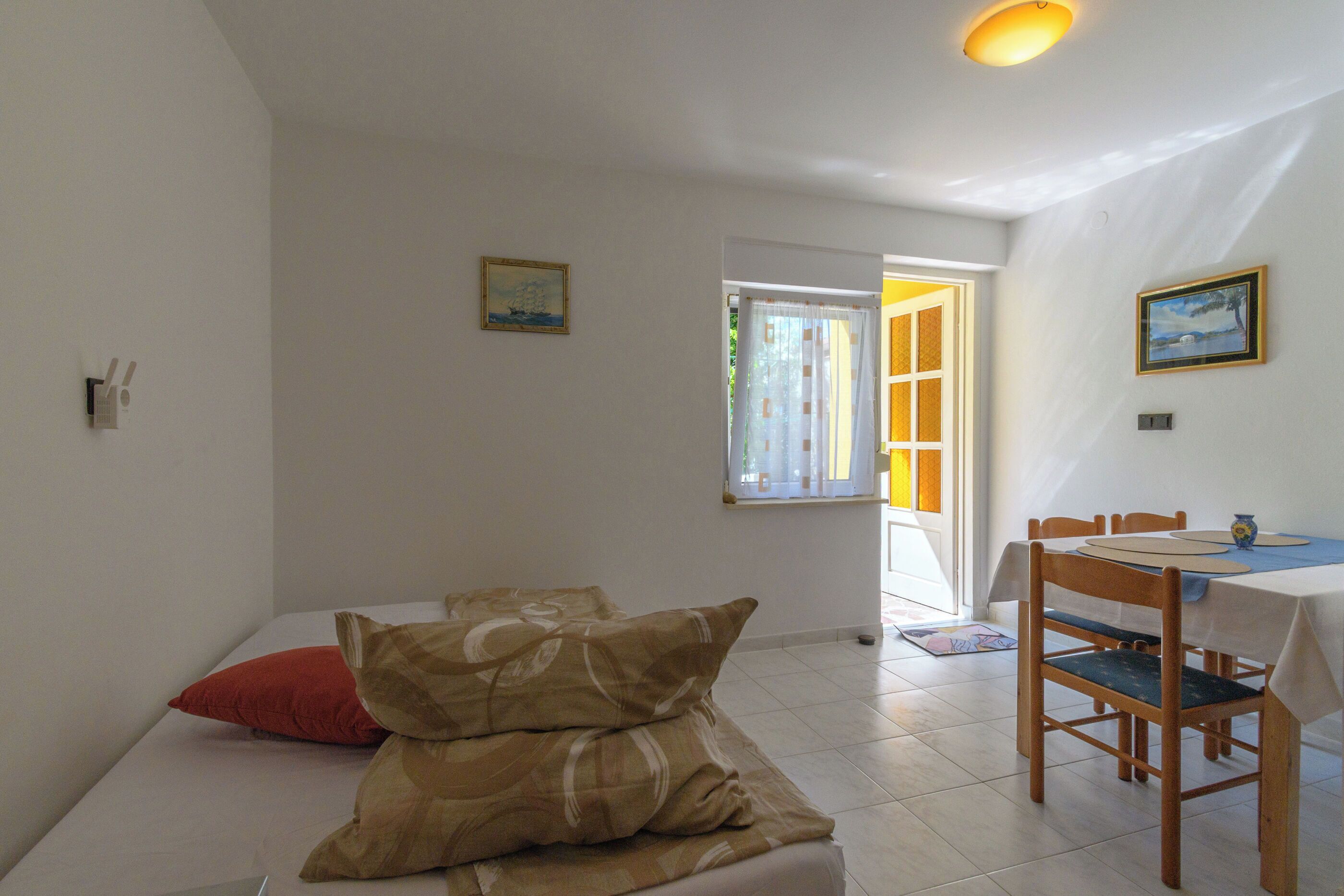 A room with a bed, a dining table, chairs, and a window with curtains.