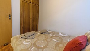 Une chambre à coucher avec un lit, une armoire en bois et un oreiller rouge.