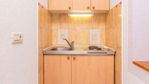 A compact kitchen with a sink, a stove, and wooden cabinets. - Apartments Branko (Dugi Rat)