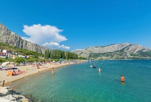 A beach with clear water, people swimming, and mountains in the background. - Apartments Branko (Dugi Rat)