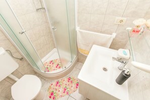Ein Badezimmer mit Duschkabine, Toilette, Waschbecken und Handtuchhalter.